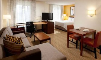 Sonesta ES Suites San Antonio Downtown Alamo Plaza double bed guest room living area, featuring table and chairs, sofa, windows, and a TV.