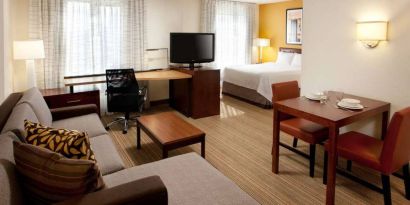 Sonesta ES Suites San Antonio Downtown Alamo Plaza double bed guest room living area, featuring table and chairs, sofa, windows, and a TV.