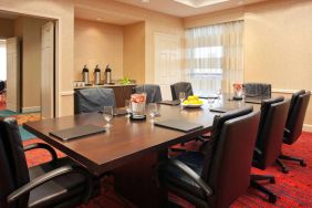 Hotel meeting room with long wooden table, large window, and eight leather chairs.