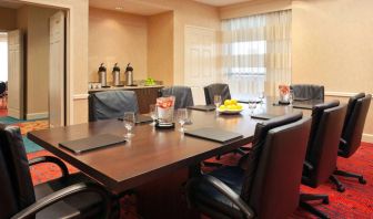 Hotel meeting room with long wooden table, large window, and eight leather chairs.