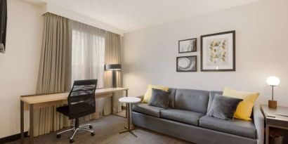 Guest room workspace desk and chair, with a window and nearby sofa, at Sonesta ES Suites Reno.