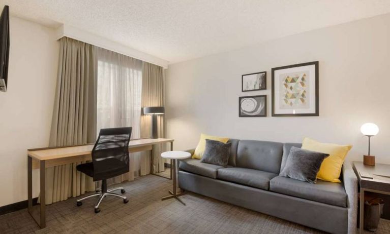 Guest room workspace desk and chair, with a window and nearby sofa, at Sonesta ES Suites Reno.