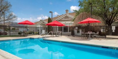 Sonesta ES Suites Reno’s outdoor pool has shaded tables and chairs by the side.