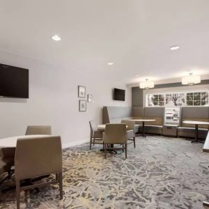 Lounge seating area, featuring tables and chairs, plus booth seating and a wall-mounted TV, at Sonesta ES Suites Reno.