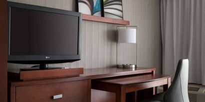 Guest room workspace in Sonesta Select Los Angeles LAX El Segundo, with chair, desk, lamp, and TV.