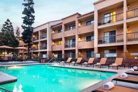 Sonesta Select Los Angeles LAX El Segundo’s outdoor pool has shaded tables and chairs, as well as sun loungers, by the side.