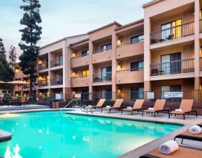 Sonesta Select Los Angeles LAX El Segundo’s outdoor pool has shaded tables and chairs, as well as sun loungers, by the side.