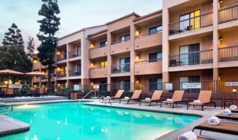 Sonesta Select Los Angeles LAX El Segundo’s outdoor pool has shaded tables and chairs, as well as sun loungers, by the side.