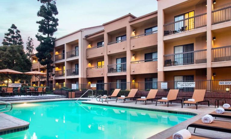 Sonesta Select Los Angeles LAX El Segundo’s outdoor pool has shaded tables and chairs, as well as sun loungers, by the side.