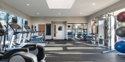 Fitness center equipped with free weights, gym balls, a TV, and various exercise machines at Sonesta Select Los Angeles LAX El Segundo.