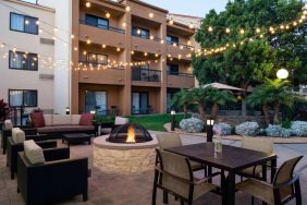 Fire pit with armchairs next to it, and more seating nearby, at Sonesta Select Los Angeles LAX El Segundo.