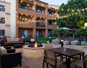 Fire pit with armchairs next to it, and more seating nearby, at Sonesta Select Los Angeles LAX El Segundo.