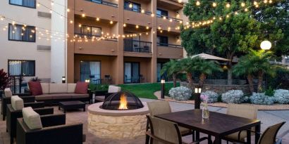 Fire pit with armchairs next to it, and more seating nearby, at Sonesta Select Los Angeles LAX El Segundo.