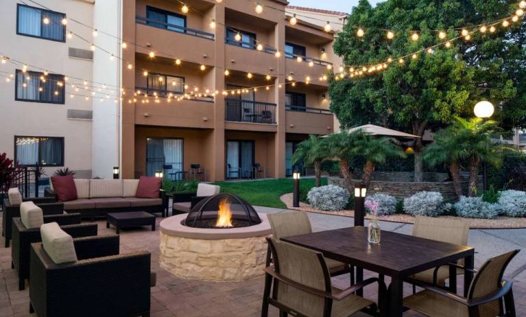 Fire pit with armchairs next to it, and more seating nearby, at Sonesta Select Los Angeles LAX El Segundo.