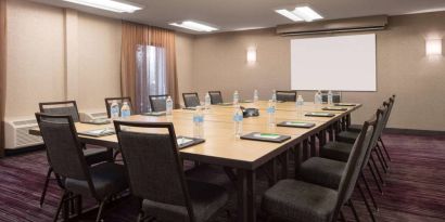 Hotel meeting room, with window, whiteboard, and seating for 14 around a large wooden table.