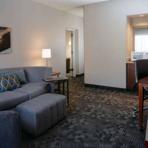 Guest room living area with sofa, chair, and TV at Sonesta Select Kansas City South Overland Park.