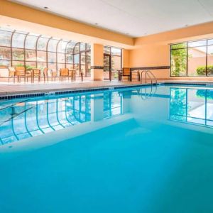 Indoor pool with large windows and tables and chairs at Sonesta Select Kansas City South Overland Park.