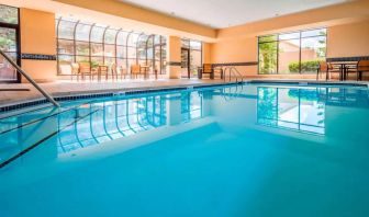 Indoor pool with large windows and tables and chairs at Sonesta Select Kansas City South Overland Park.