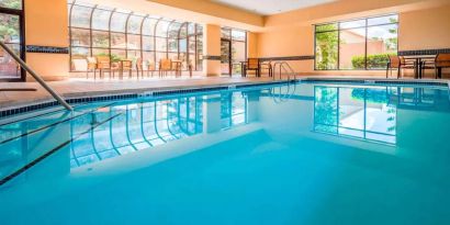 Indoor pool with large windows and tables and chairs at Sonesta Select Kansas City South Overland Park.