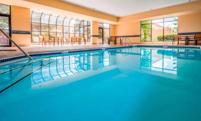 Indoor pool with large windows and tables and chairs at Sonesta Select Kansas City South Overland Park.