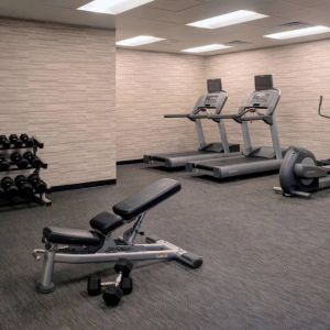 Fitness center furnished with free weights, assorted exercise machines, and a TV at Sonesta Select Kansas City South Overland Park.