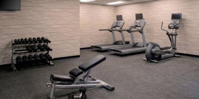 Fitness center furnished with free weights, assorted exercise machines, and a TV at Sonesta Select Kansas City South Overland Park.