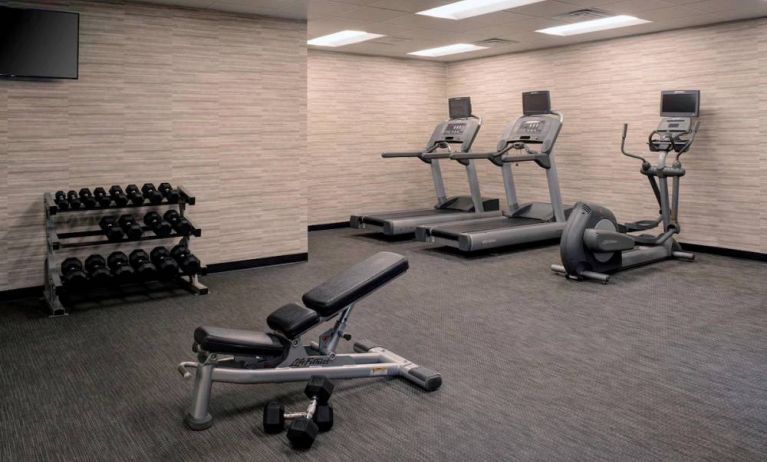 Fitness center furnished with free weights, assorted exercise machines, and a TV at Sonesta Select Kansas City South Overland Park.