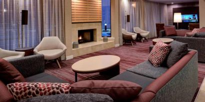 Sonesta Select Kansas City South Overland Park’s lobby lounge features a fireplace and wall-mounted TV, with extensive sofa seating and comfy chairs.