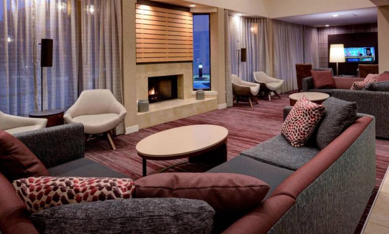 Sonesta Select Kansas City South Overland Park’s lobby lounge features a fireplace and wall-mounted TV, with extensive sofa seating and comfy chairs.