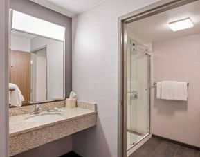 Sonesta Select Pleasant Hill guest bathroom, including shower, lavatory, mirror, and sink.