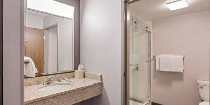 Sonesta Select Pleasant Hill guest bathroom, including shower, lavatory, mirror, and sink.