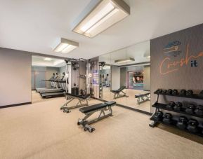 Sonesta Select Pleasant Hill’s fitness center features free weights, a mirrored wall, and various exercise machines.