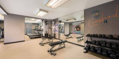 Sonesta Select Pleasant Hill’s fitness center features free weights, a mirrored wall, and various exercise machines.