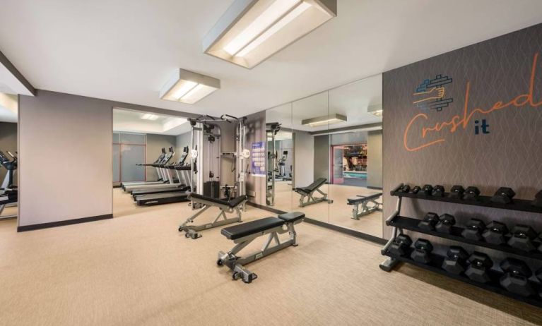 Sonesta Select Pleasant Hill’s fitness center features free weights, a mirrored wall, and various exercise machines.