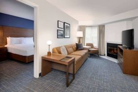 Guest room living area in Sonesta ES Suites Atlanta Alpharetta North Point Mall, with sofa, fireplace,  and TV.