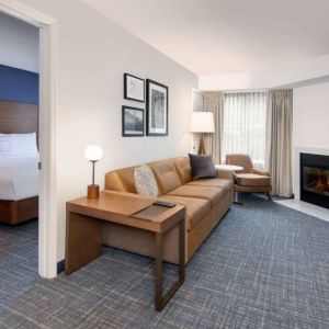 Guest room living area in Sonesta ES Suites Atlanta Alpharetta North Point Mall, with sofa, fireplace,  and TV.