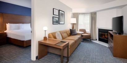 Guest room living area in Sonesta ES Suites Atlanta Alpharetta North Point Mall, with sofa, fireplace,  and TV.