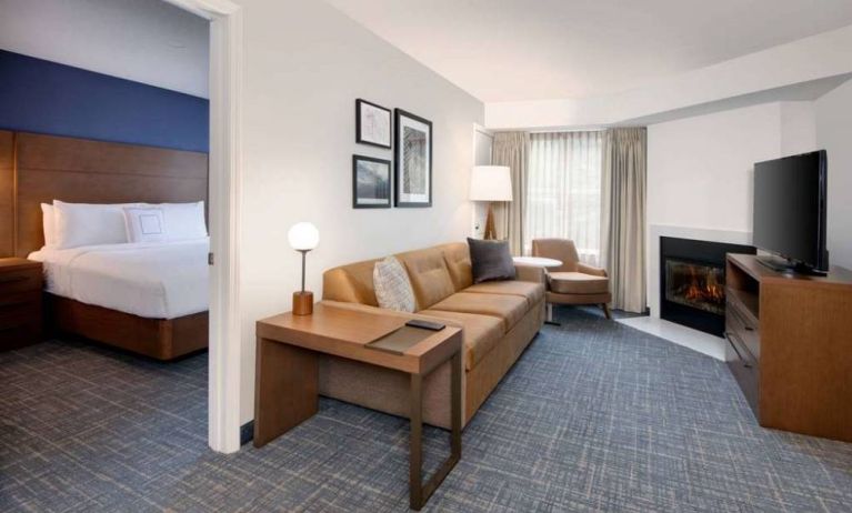 Guest room living area in Sonesta ES Suites Atlanta Alpharetta North Point Mall, with sofa, fireplace,  and TV.