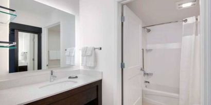 Guest bathroom in Sonesta ES Suites Atlanta Alpharetta North Point Mall featuring shower-equipped bath, lavatory, mirror, and sink.