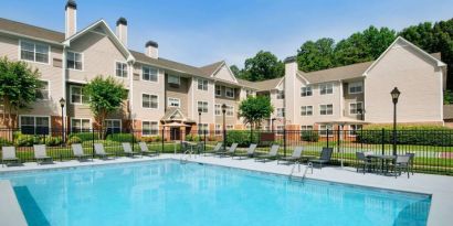 Sonesta ES Suites Atlanta Alpharetta North Point Mall’s outdoor pool has tables and chairs, and sun loungers, by the side.