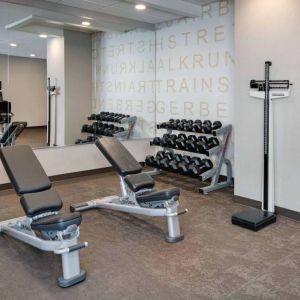 Hotel fitness center equipped with free weights, benches, and various exercise machines.