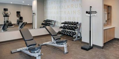 Hotel fitness center equipped with free weights, benches, and various exercise machines.