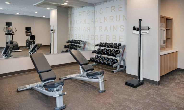 Hotel fitness center equipped with free weights, benches, and various exercise machines.