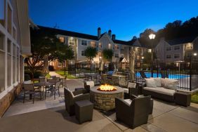 Patio area with fire pit, barbecue, tables and chairs, and armchairs, at Sonesta ES Suites Atlanta Alpharetta North Point Mall.