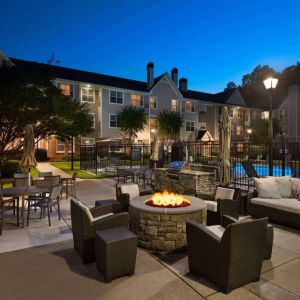 Patio area with fire pit, barbecue, tables and chairs, and armchairs, at Sonesta ES Suites Atlanta Alpharetta North Point Mall.