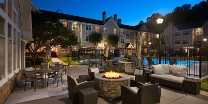 Patio area with fire pit, barbecue, tables and chairs, and armchairs, at Sonesta ES Suites Atlanta Alpharetta North Point Mall.