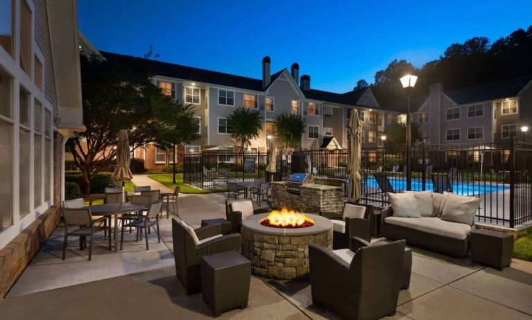 Patio area with fire pit, barbecue, tables and chairs, and armchairs, at Sonesta ES Suites Atlanta Alpharetta North Point Mall.