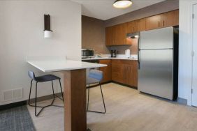 Sonesta ES Suites Fort Worth Fossil Creek guest room kitchen, featuring fridge-freezer, microwave, and table and chairs.