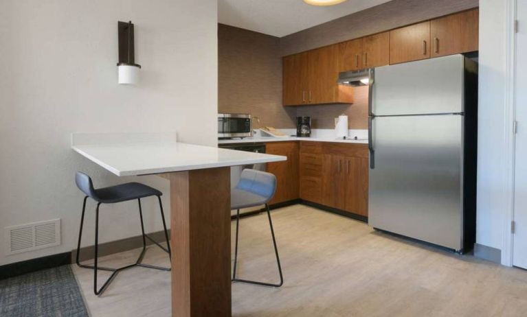 Sonesta ES Suites Fort Worth Fossil Creek guest room kitchen, featuring fridge-freezer, microwave, and table and chairs.