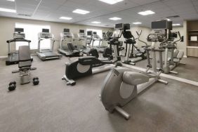 Fitness center at Sonesta ES Suites Fort Worth Fossil Creek, featuring free weights, a mirrored wall, and range of exercise machines.